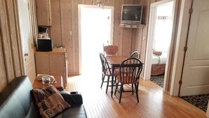A cozy living room with a black leather sofa, wooden dining table with chairs, and a TV mounted on the wall. - Nevada City Inn (Nevada City)