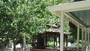 A covered outdoor area with a wooden deck, a gazebo, and a building with a green roof. - Nevada City Inn (Nevada City)