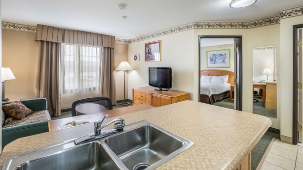 Une chambre d’hôtel avec un lit, un bureau, une télévision, un lavabo et une fenêtre avec des rideaux.