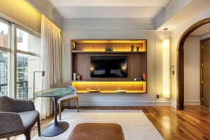 A modern living room with a flat-screen TV, a dining table with chairs, and a wooden floor.