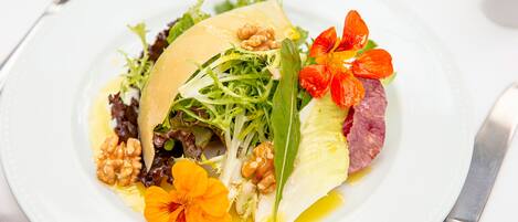 Un plato blanco con ensalada, nueces y flores.