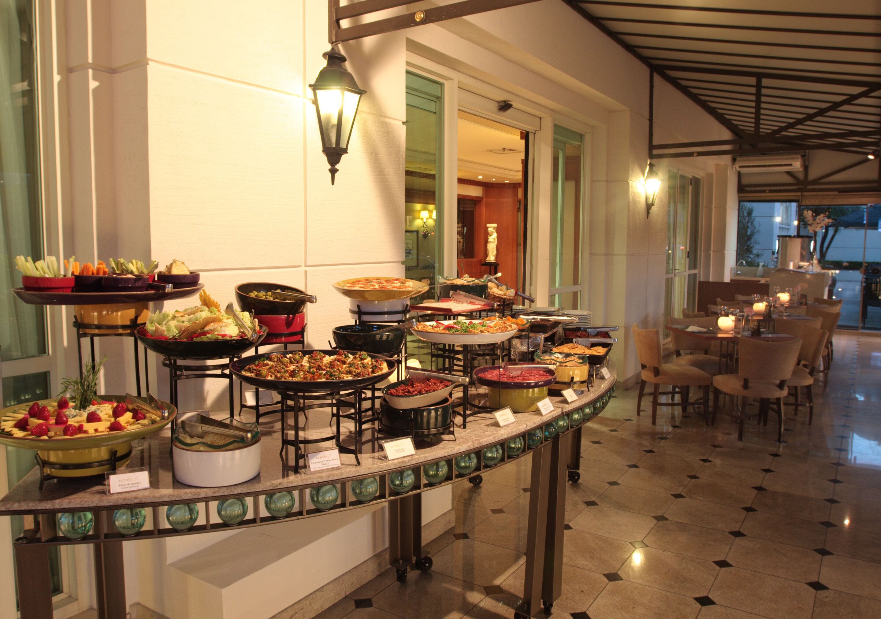 A buffet with various dishes, a seating area with tables and chairs, and a well-lit interior.