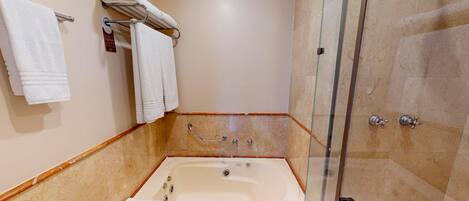 Un baño con bañera, inodoro, ducha y cabina de ducha con paredes de vidrio.