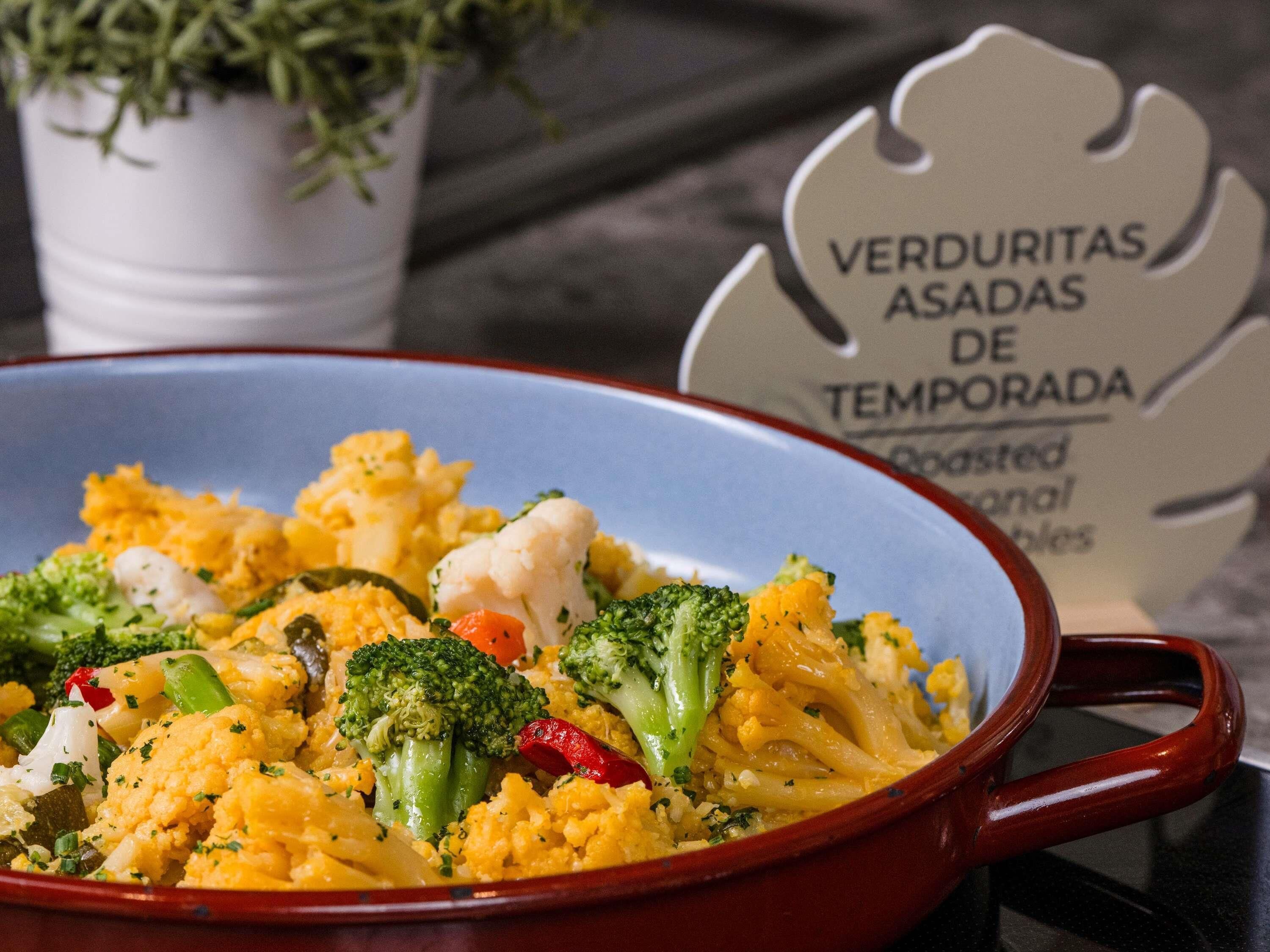 Un plato de verduras en un bol rojo con un cartel de fondo.