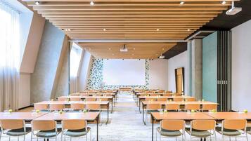A conference room with long tables and chairs, a projector, and a large screen.