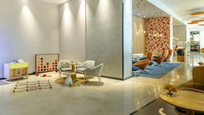A modern hotel lobby with a seating area, a children's play area, and a vibrant wall design. - Novotel Sevilla (Seville)