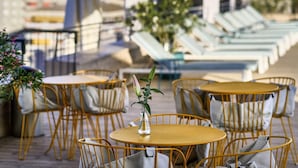 Outdoor seating with tables and chairs, a potted plant, and a view of the cityscape. - Novotel Sevilla (Seville)