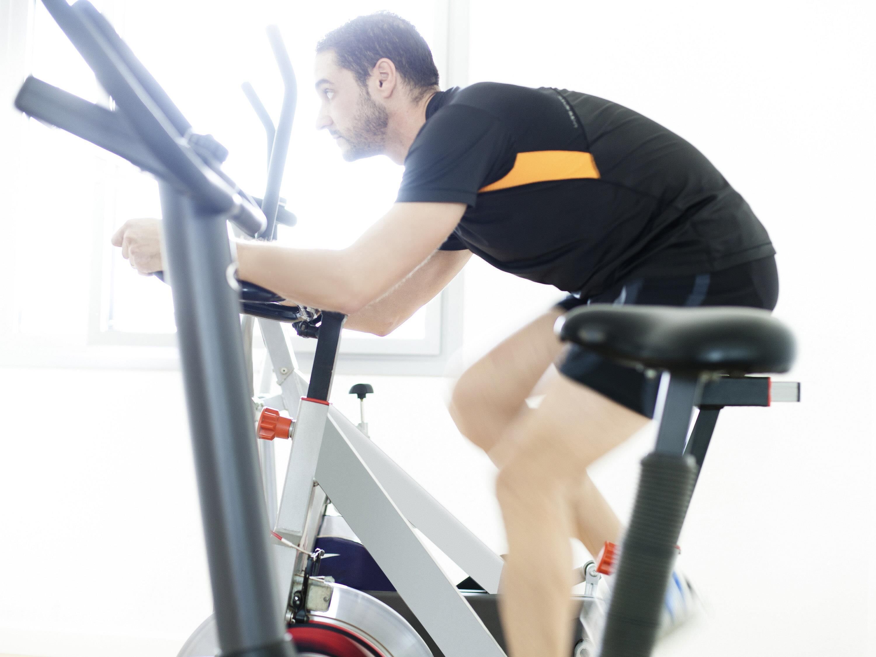 A person using an exercise bike in a room with a window and a door.
