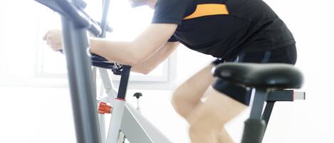 A person using an exercise bike in a room with a window and a door.