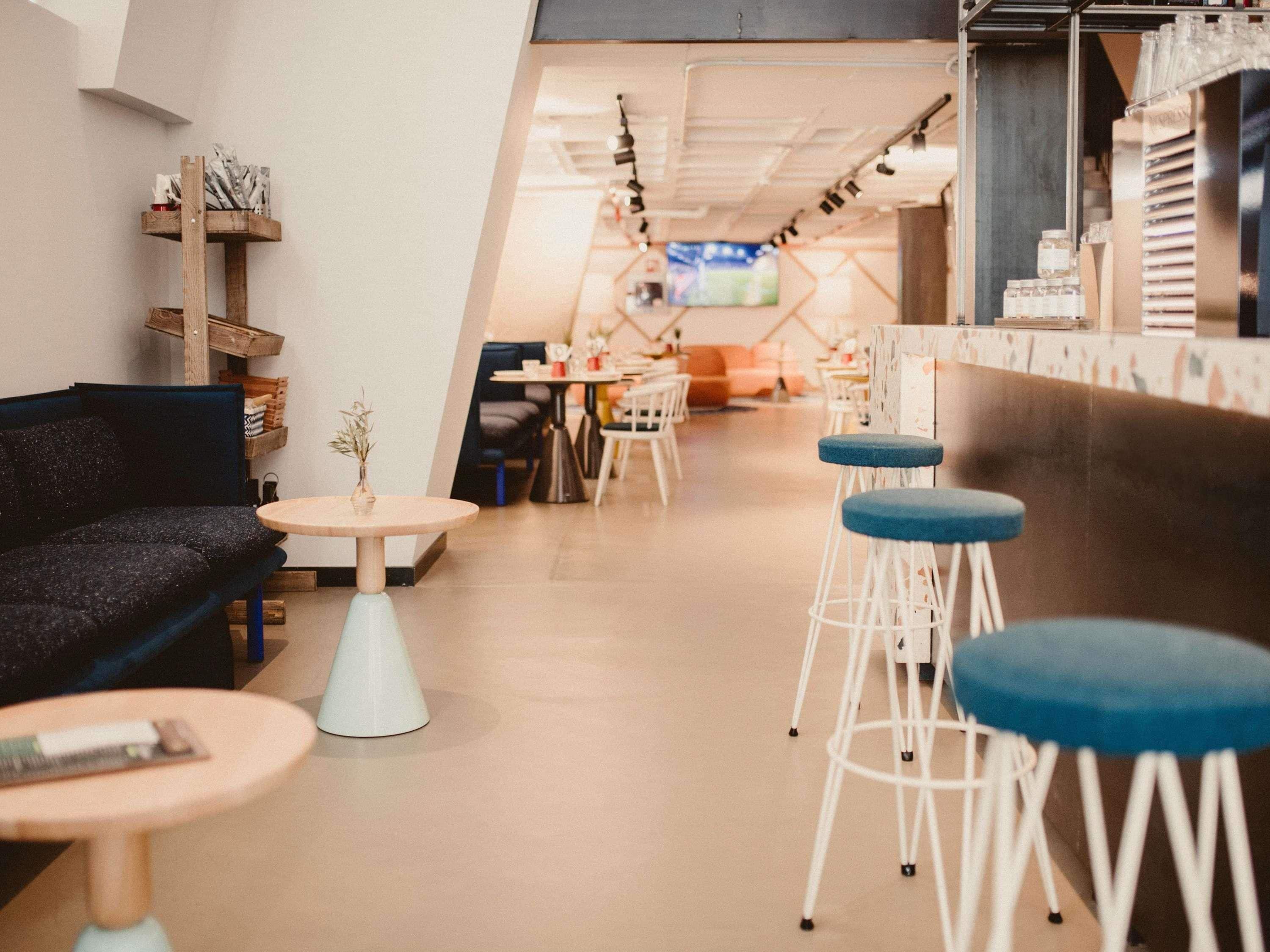 A modern bar area with stools, a sofa, and tables.