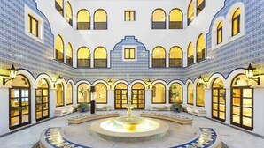 Une cour intérieure avec une fontaine centrale, des fenêtres en arc de cercle et des murs recouverts de carreaux.