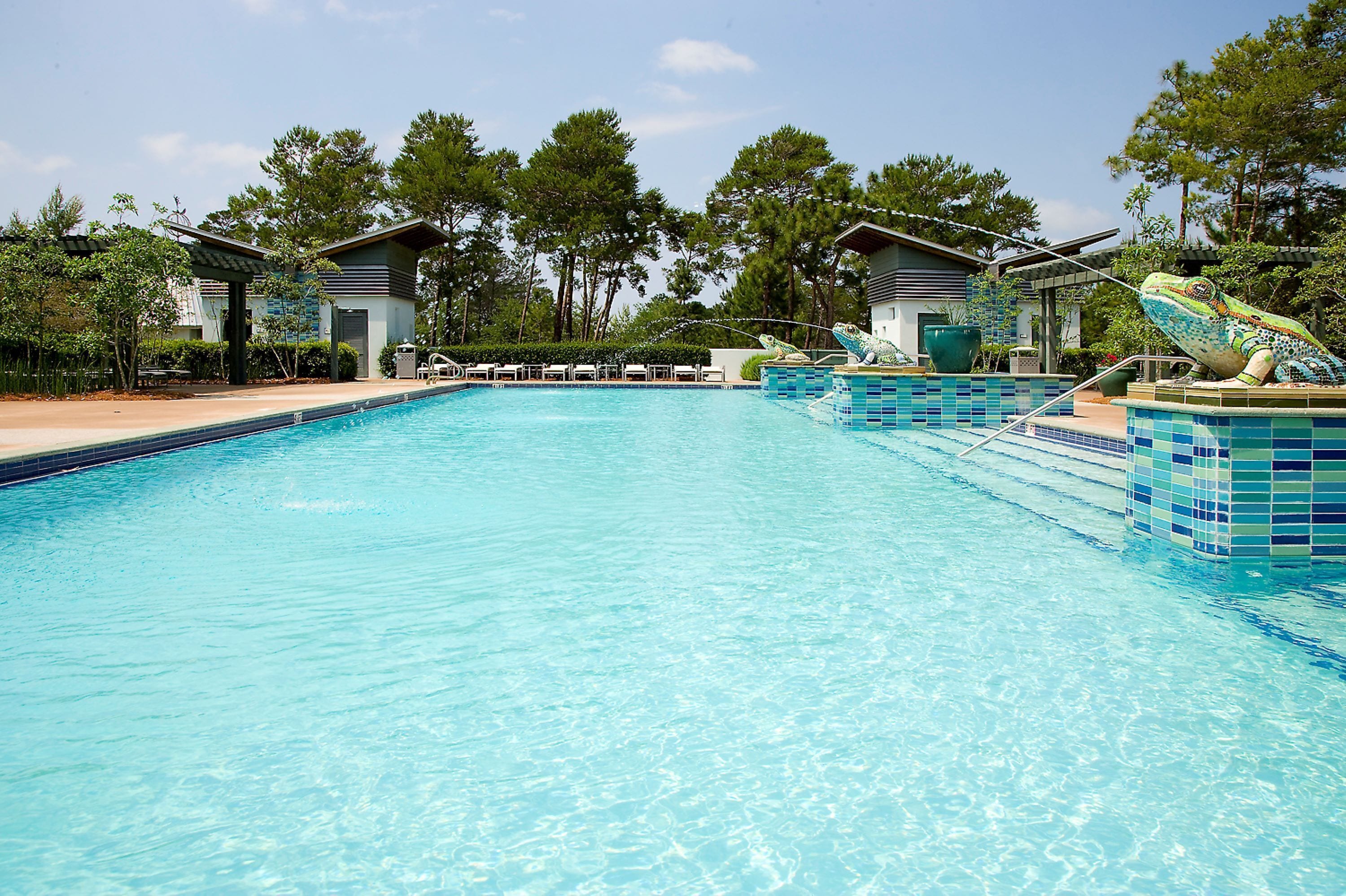 A swimming pool with clear blue water, surrounded by lounge chairs and a gazebo.