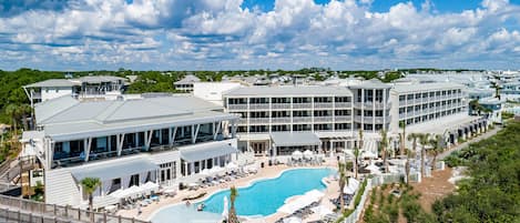A resort with a large pool, multiple buildings, and a wooden bridge.