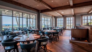 A spacious restaurant with large windows offering ocean views, wooden flooring, and modern seating arrangements. - WaterColor Inn & Resort (Santa Rosa Beach)