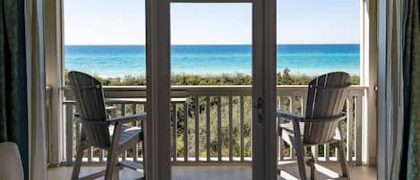 A balcony with two Adirondack chairs facing a clear view of the ocean.