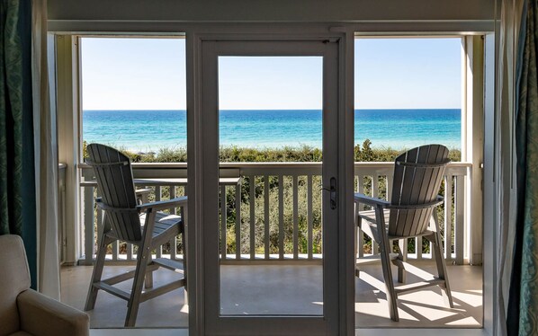 A balcony with two Adirondack chairs facing a clear view of the ocean.