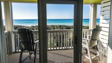 A balcony with two Adirondack chairs facing a view of the ocean.