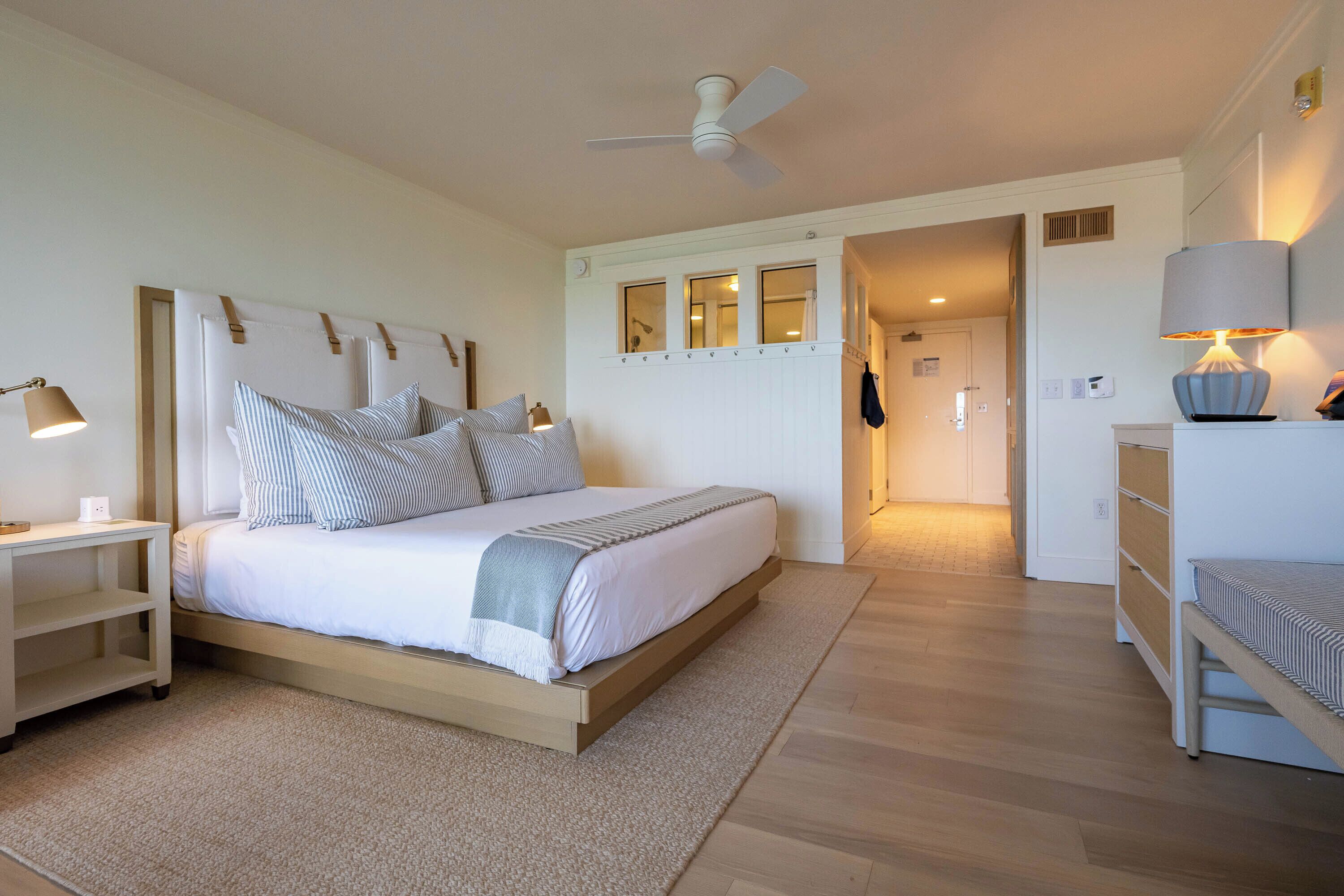 A bedroom with a bed, bedside tables, a ceiling fan, a lamp, and a dresser.