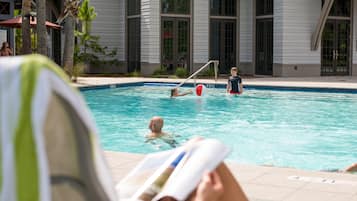 Guests can enjoy a refreshing swim in the pool surrounded by a deck and palm trees.