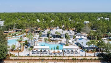 An aerial view of a resort with multiple swimming pools, palm trees, and a variety of outdoor seating areas.