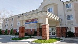 Un hotel con una entrada destacada, un cartel que indica 'Candlewood Suites' y un estacionamiento al frente.