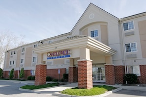 Un hotel con una entrada destacada, un cartel que indica 'Candlewood Suites' y un estacionamiento al frente.