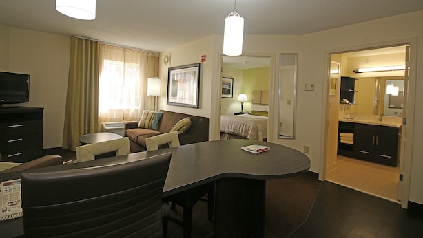 A hotel room with a dining area, a TV, a bed, and a bathroom. - Candlewood Suites Newport News/Yorktown by IHG (Yorktown)