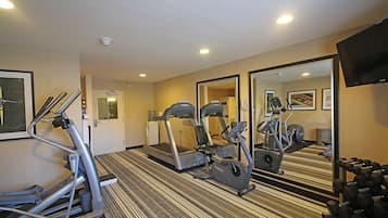 Un gimnasio hotelero con cintas de correr, elípticas y pesas sueltas.