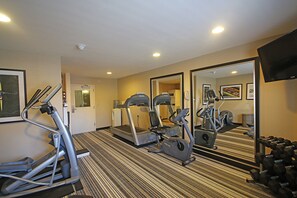 A hotel gym with treadmills, elliptical machines, and free weights.