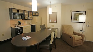 A modern kitchen with a microwave, stove, and cabinets. There is a dining table with chairs and a lamp. - Candlewood Suites Newport News/Yorktown by IHG (Yorktown)