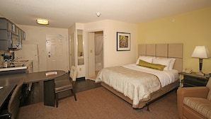 A hotel room with a bed, a desk, a chair, a bathroom, and a nightstand with a lamp. - Candlewood Suites Newport News/Yorktown by IHG (Yorktown)