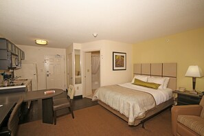 A hotel room with a bed, a desk, a chair, a bathroom, and a nightstand with a lamp. - Candlewood Suites Newport News/Yorktown by IHG (Yorktown)