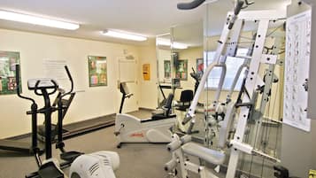 A fitness center with cardio equipment, weight machines, and instructional posters.