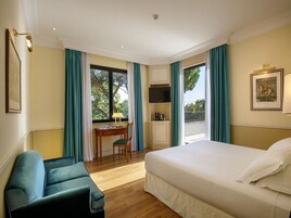 A hotel room with a bed, a desk, a chair, and a television.