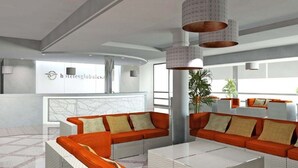 Una hall d'hotel moderna con divani arancioni, un pannello in vetro e la reception.