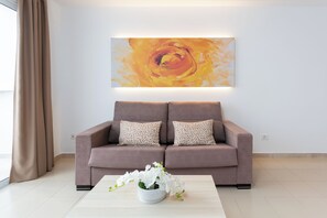A modern living room with a sofa, a coffee table, and a wall-mounted painting.