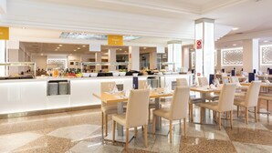 Un ristorante moderno in hotel con area buffet, diversi tavoli e un arredamento interno pulito e contemporaneo.
