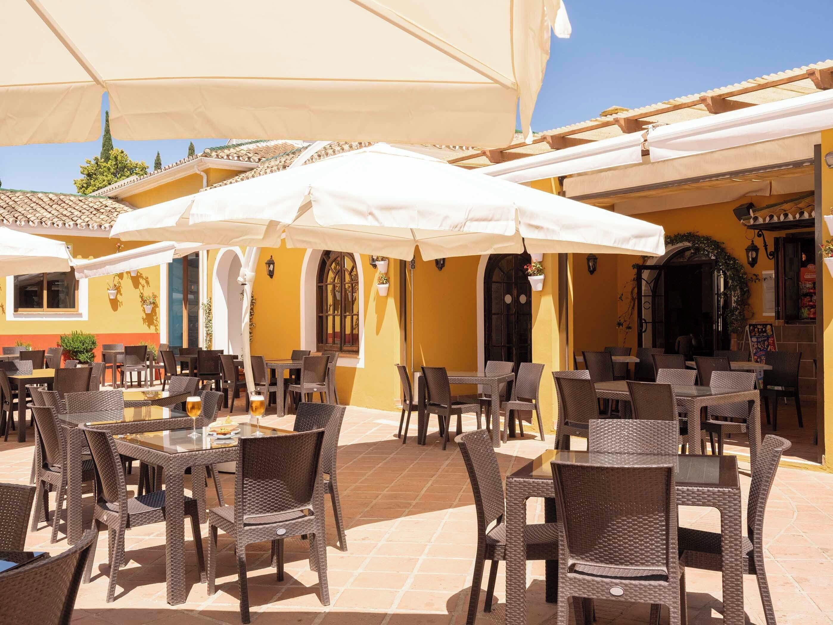An outdoor patio area with wicker furniture and white umbrellas.