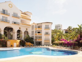 Un hôtel doté d’une piscine, de plusieurs balcons et d’un espace jardin aménagé avec des chaises longues.