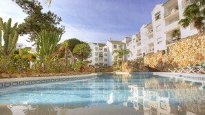 A swimming pool with clear blue water, surrounded by white buildings with balconies, and various plants including cacti and palm trees. - Ona Alanda Club Marbella (Marbella)