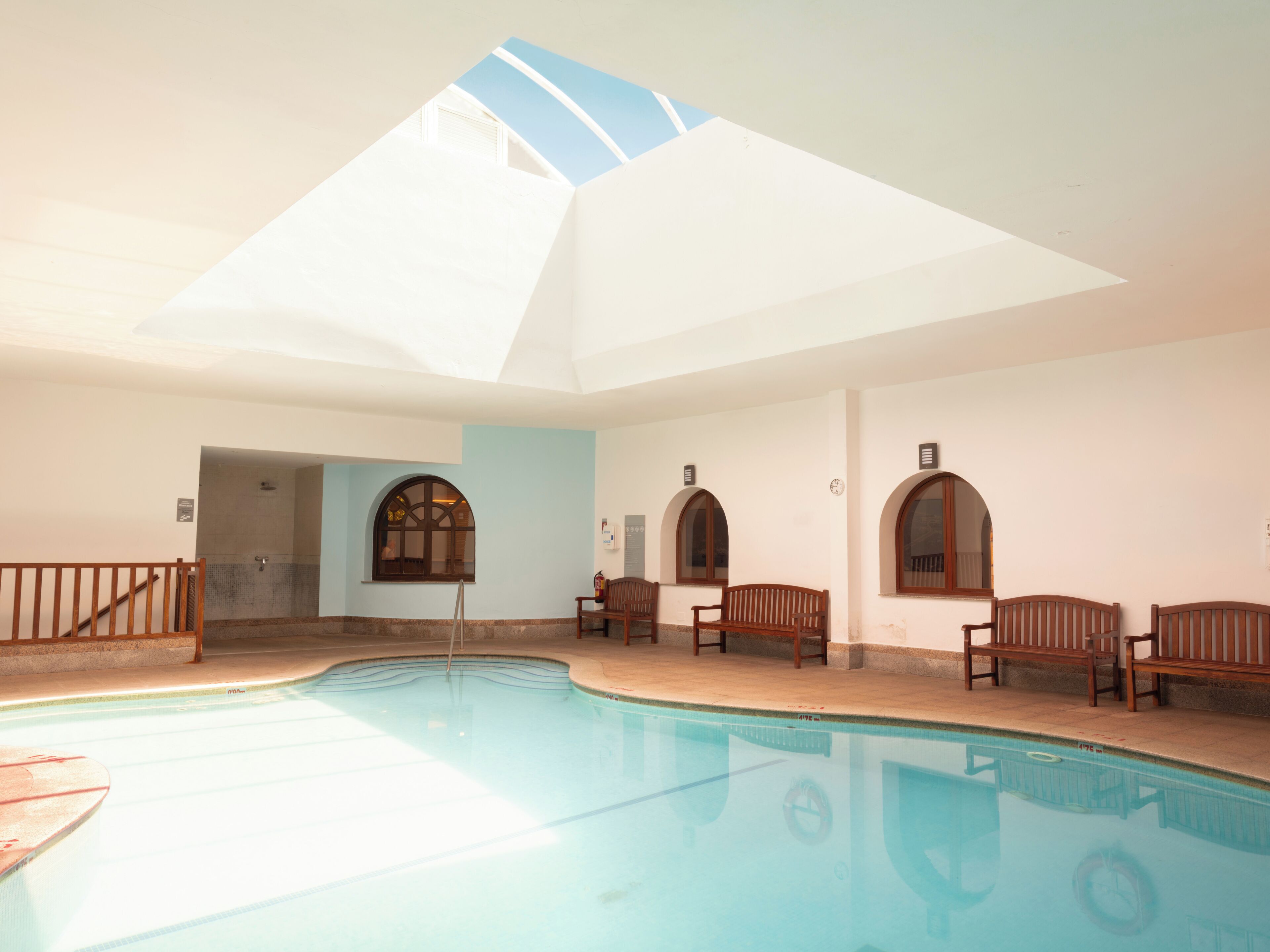 Una piscina interior con bancos y tragaluces.