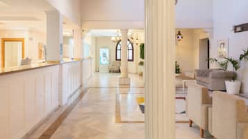 A hotel lobby with a reception desk, seating area, and a large column.