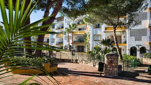A courtyard with a stone wall, a palm tree, and a building with balconies and a sign reading "ALMERIA". - Ona Alanda Club Marbella (Marbella)