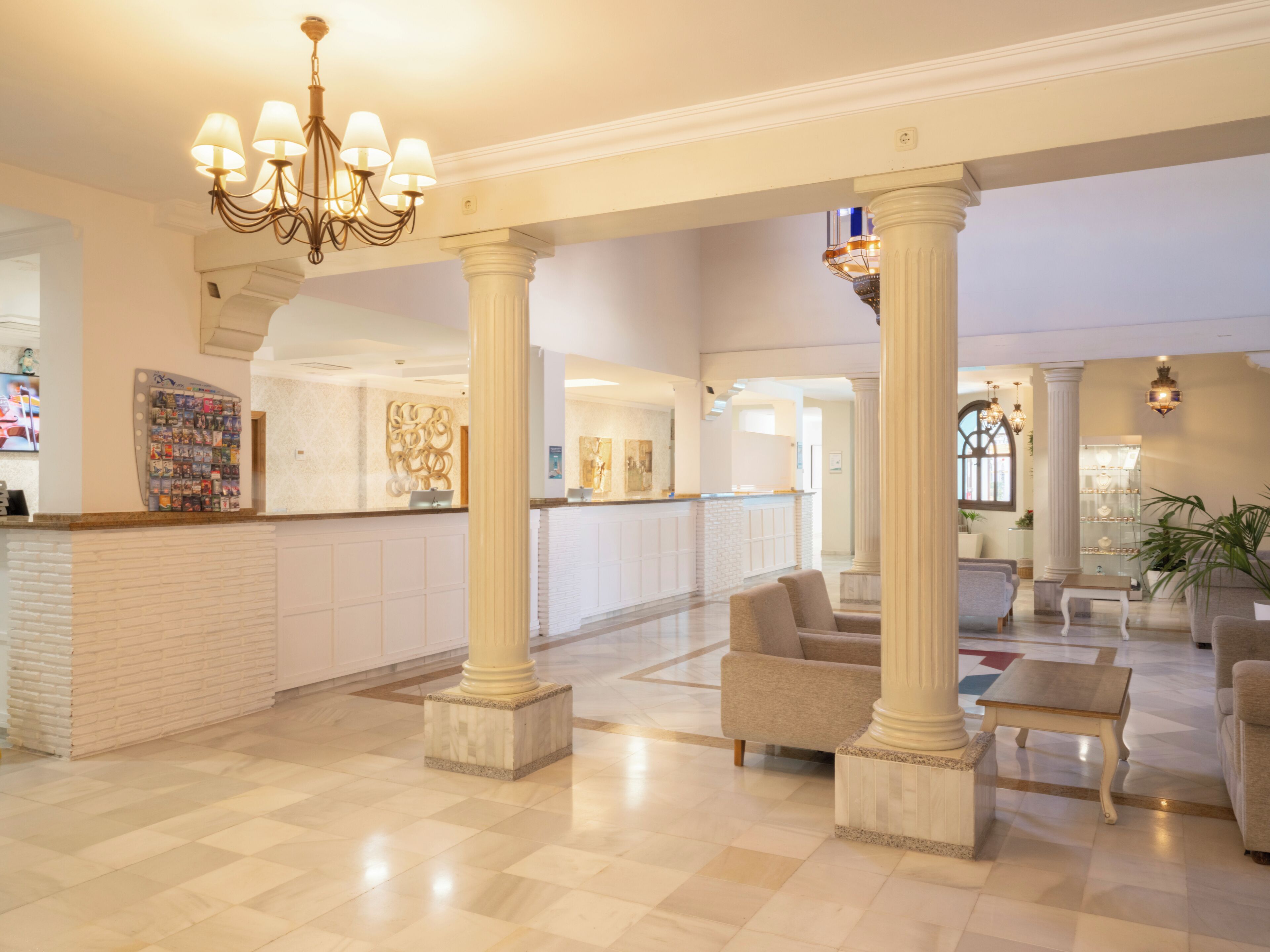 A spacious lobby with marble flooring, a reception desk, and seating areas.