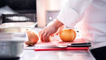 Un chef corta una cebolla sobre una tabla de cortar en una cocina.
