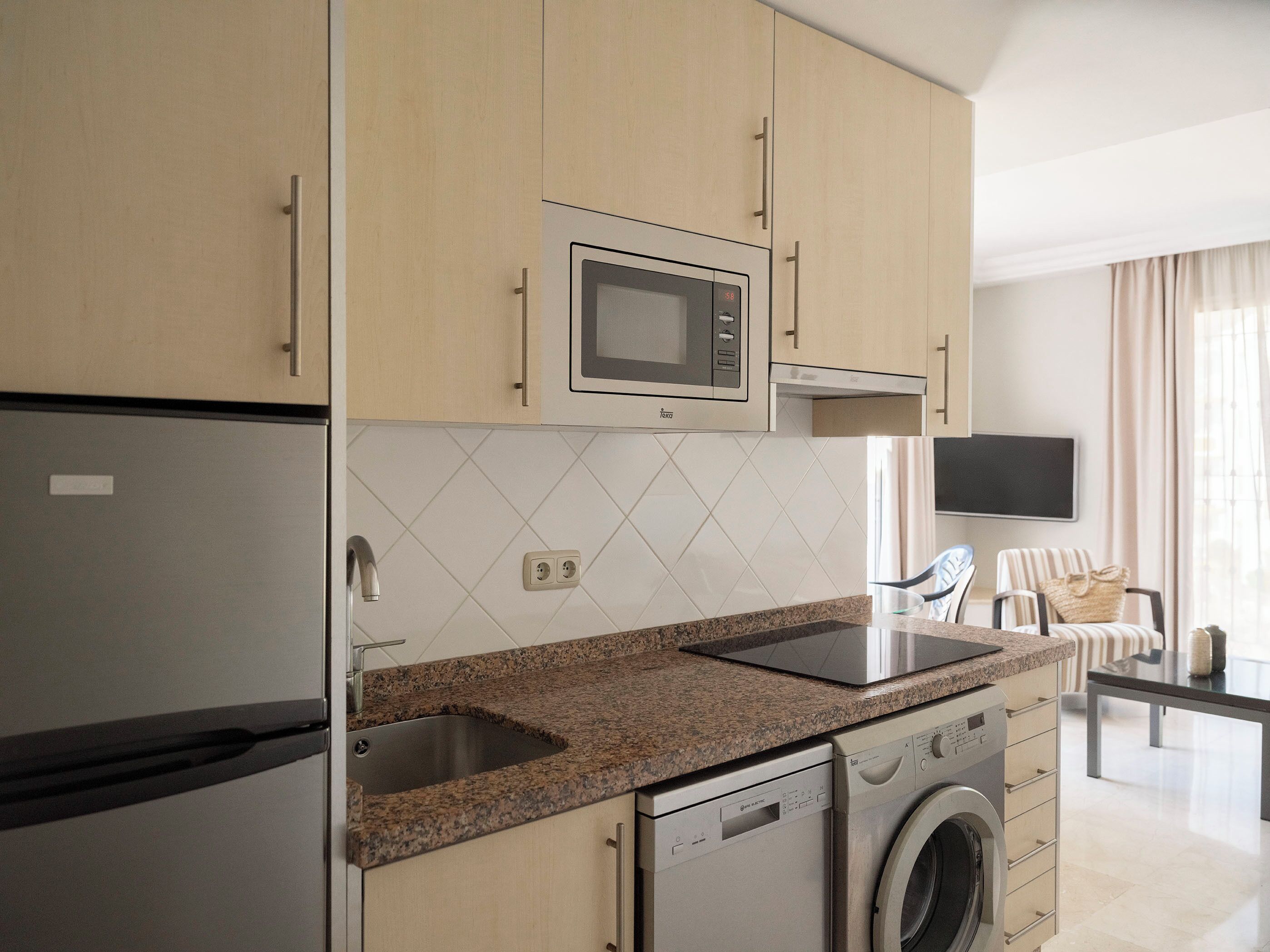 A modern kitchen with a built-in microwave, dishwasher, and granite countertop.