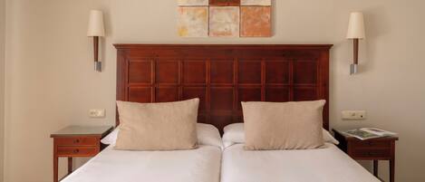 A double bed with a wooden headboard, two bedside tables, and a wall-mounted artwork.
