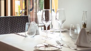 A dining table set with wine glasses, plates, and cutlery, with a view of greenery through a window. - Ona Alanda Club Marbella (Marbella)