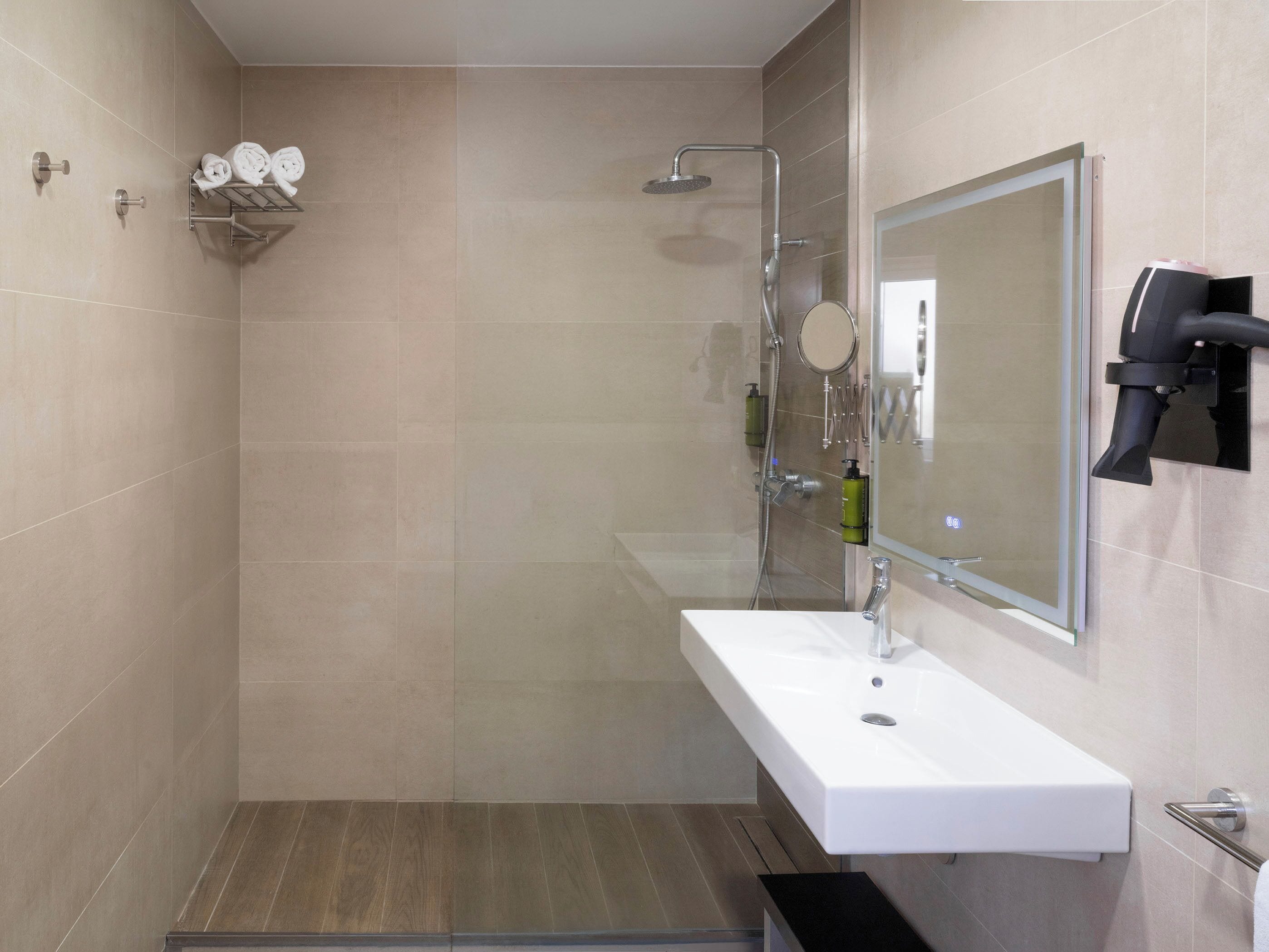 A modern bathroom with a shower, sink, and towel rack.