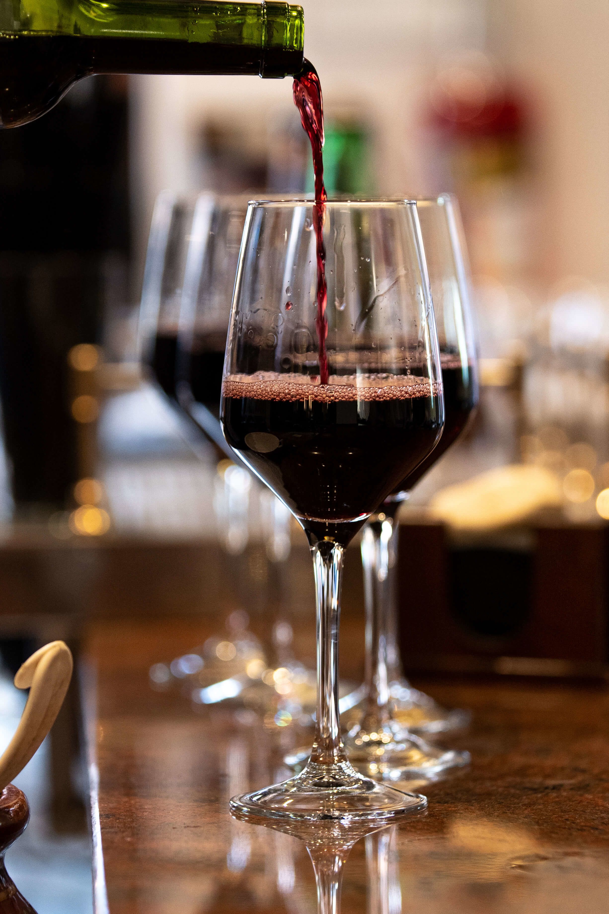 A bottle of red wine being poured into a glass.